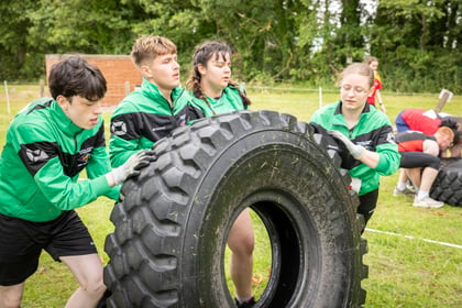 Cadets wearing green and black push over truck tire