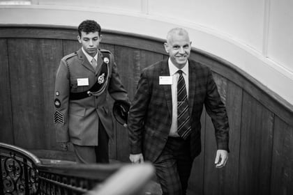 An elderly man walks up the stairs smiling with his son following behind him