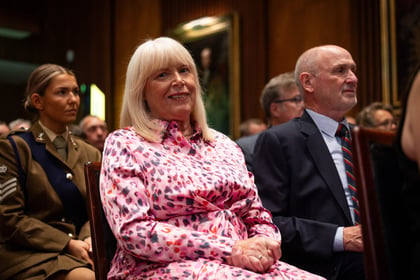 Lady with blonde hair and a pink dress sits down
