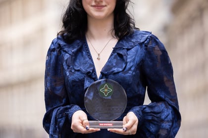 Female holds an award while wearing a blue blouse