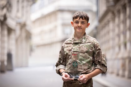 Male cadet holds his ACCT UK Award while wearing uniform
