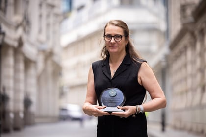 Mother of cadet holds his ACCT UK Award wearing a black dress and black glasses