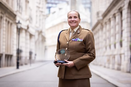 Adult volunteer wears a brown uniform holding her ACCT UK Award