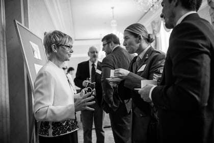 Black and white photo of people speaking holding tea cups in their hands