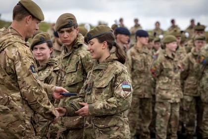 Female cadet receives a medal from an adult instructor at Cadet Cambrian Patrol 2026