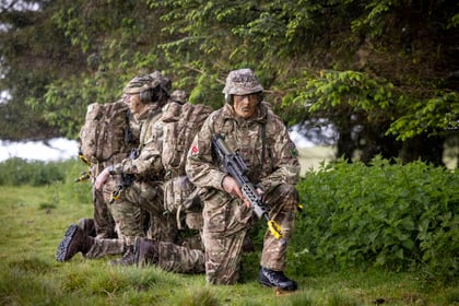Cadets kneel in position during fieldcraft exercise at Cadet Cambrian Patrol 2026 with weapons pointed to the ground