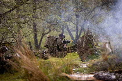A male cadet during fieldcraft exercise at Cadet Cambrian Patrol 2026 with rain falling and smoke in the air