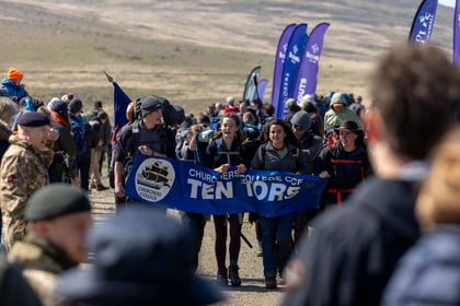 Cadets holding a blue school banner cross the finish line