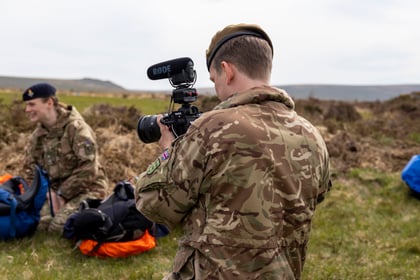 An adult volunteer holds a camera and points it at the subject of his photo