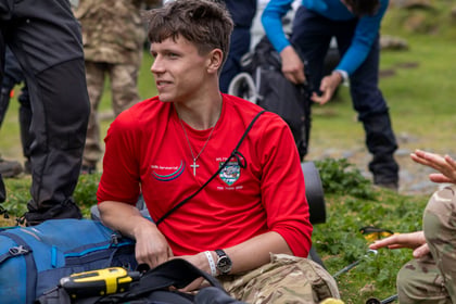 A male cadet looks to the side while wearing a red top and a cross on his neck