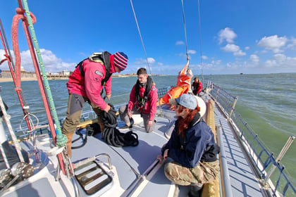 An instructor demonstrates rope handling to Army Cadets on the deck of a tall ship during sail training.