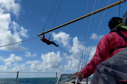 An Army Cadet climbs the mast of a tall ship while secured by a safety harness during a sail training exercise at sea.