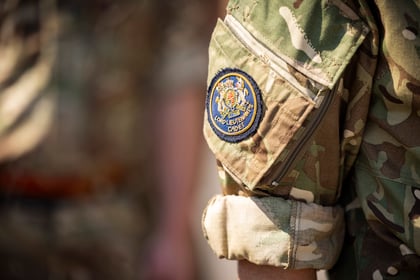 A close-up of a person wearing a camouflage military uniform, with a patch on the sleeve that reads Army Cadet Force and features a crest. The background is blurred.