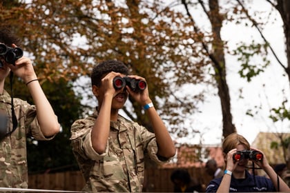 Three people in Army Cadet camouflage uniforms looking through binoculars outdoors.