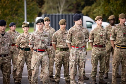 A group of Army Cadets in camouflage uniforms and berets standing in formation during an outdoor ceremony.