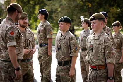 A group of Army Cadets in camouflage uniforms and berets standing in an outdoor formation.