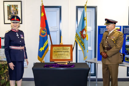 Lord Lieutenant standing in front of her plague with the Lieutenant Colonel of Essex Army Cadets. Both in formal uniform.