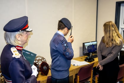 Lord Lieutenant watches a cadet simulate talking to an aircraft with a radio.
