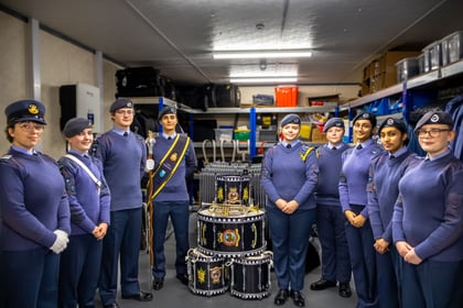 9 RAF Air Cadets pose for a photo with drums and trumpet in the middle.