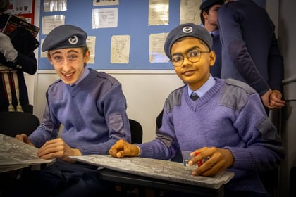Two Air Cadets sitting demonstrating map and compass skills.