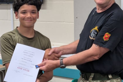 A cadet and instructor shaking hands while the adult hands over a certificate saying One Star on it