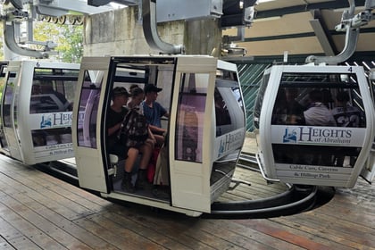 Three cadets sit in a cable car. The cable car in front has 'Heights of Abraham' written on it.