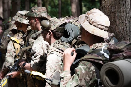 Cadets in camouflage from the back view, carrying backpacks and holding weapons