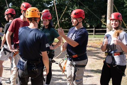 Cadets in safety gear and helmets waiting their turn on the climbing apparatus