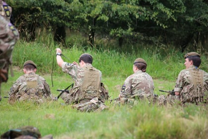 Cadets sitting down putting on rifle slings