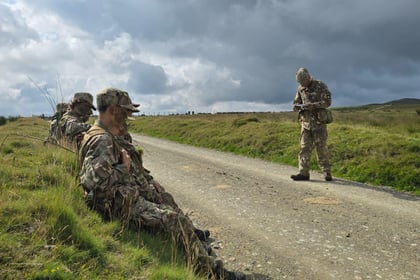 Cadets sitting on bank of road awating orders to move