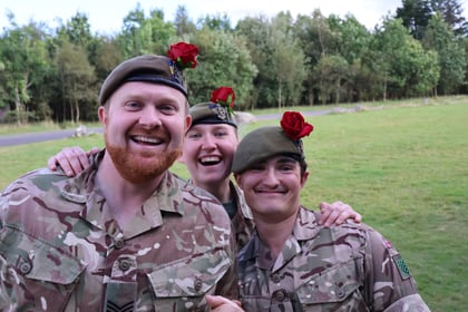 Three instructors smiling with red roses in their berets
