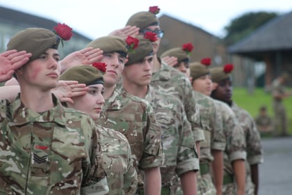 Senior Cadets saluting to the right with red roses in their berets