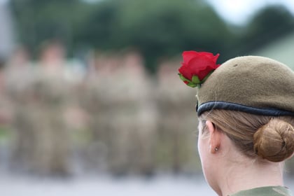 Single cadets facing away with a red rose in her beret