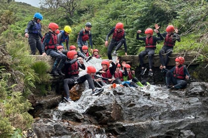 Cadets being hit by water ontop of a waterfall