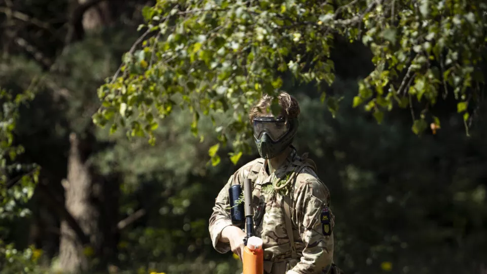 Male cadet wearing military uniform on field with a paintball rifle