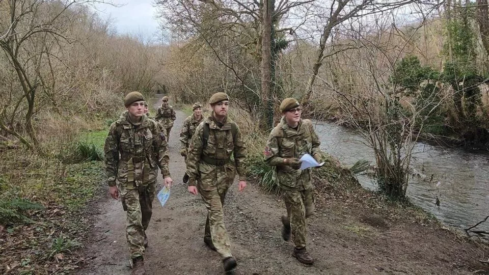 group of cadets in uniform walking beside a river during an exercise