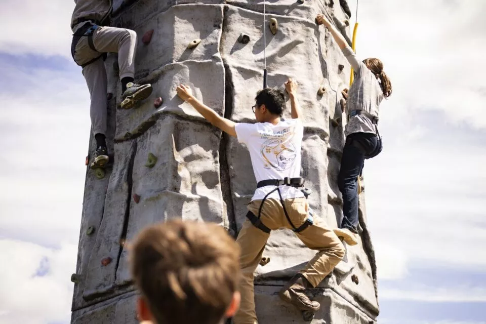 2 teenagers climbing up a static climbing wall