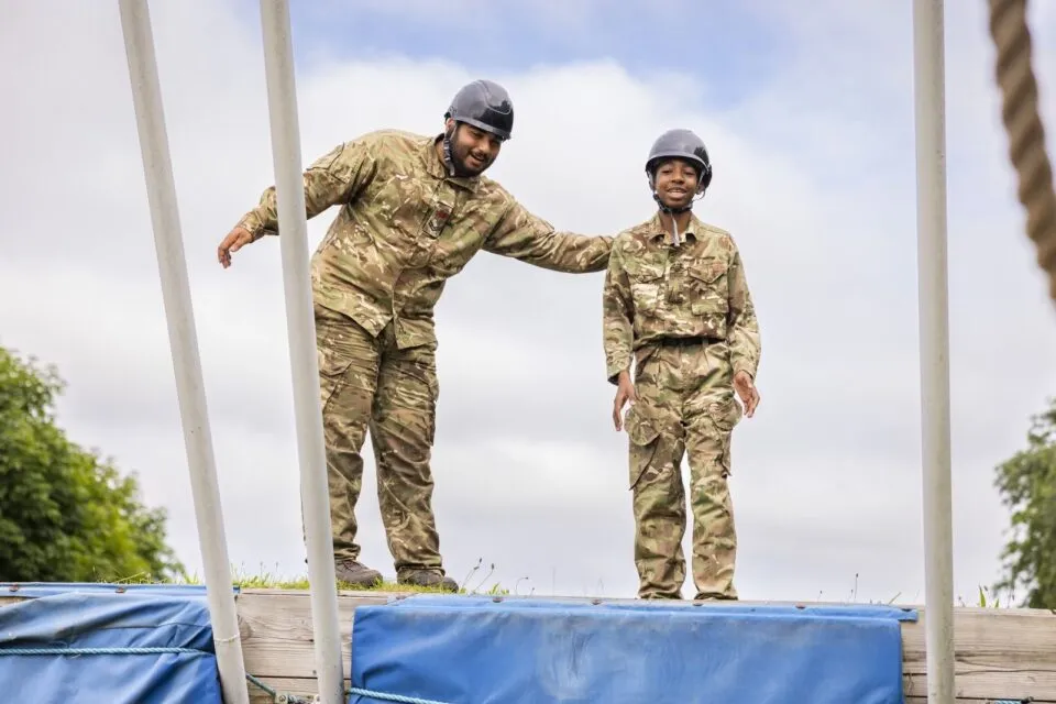 Adult volunteer encourages cadet on obstacle course