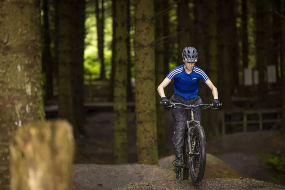person riding a bike though the woods wearing a bright blue Tshirt