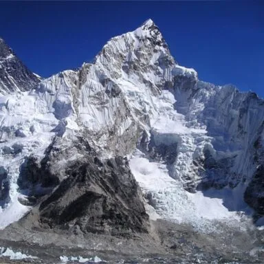 Snow-capped peaks of Mount Everest, and Nuptse against a clear blue sky in the Himalayas. Mount Everest is the tallest mountain in the world.