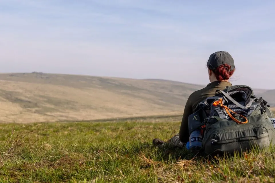 Girl sits with back towards camera looking at the hills in the distance